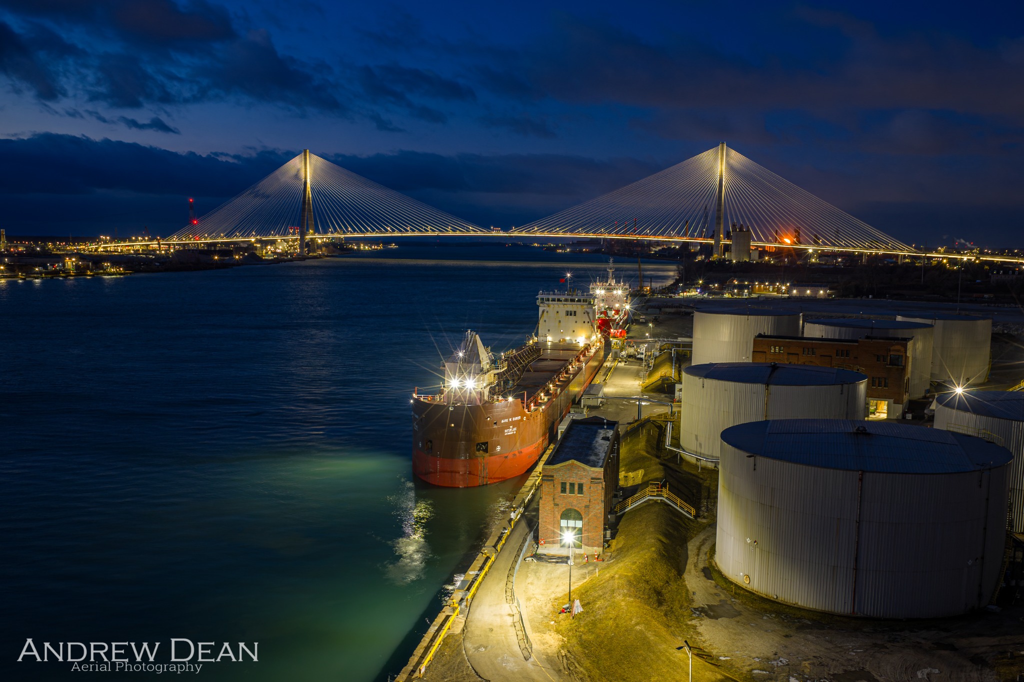 Mark W. Barker at night with the illuminated Gordie Howe International Bridge in the background